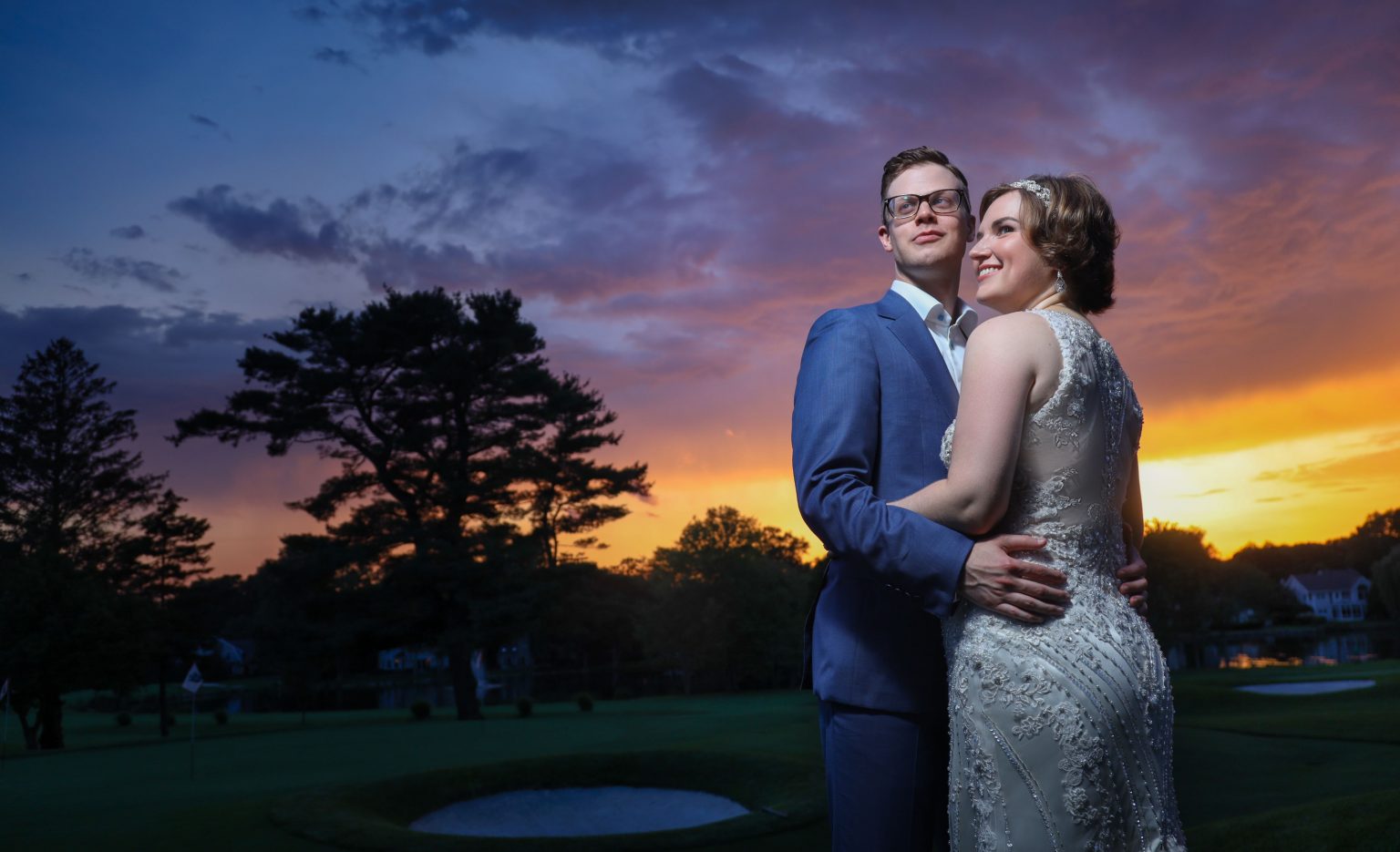 Curvy-bride and groom posing in front of a sunset