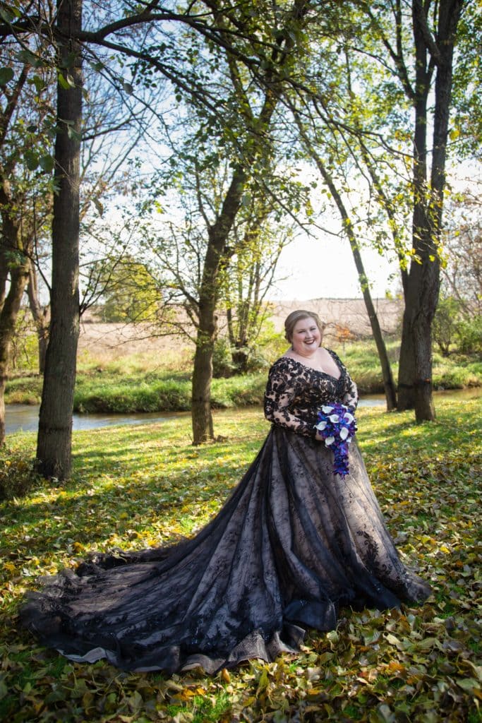 Plus-size Bride wear Black wedding dress in front of a creek and glade