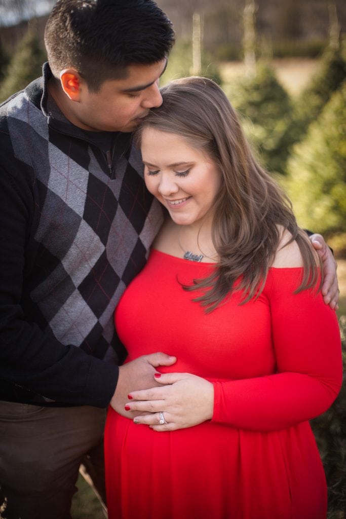 Interracial couple hugging as they mother pregnant belly