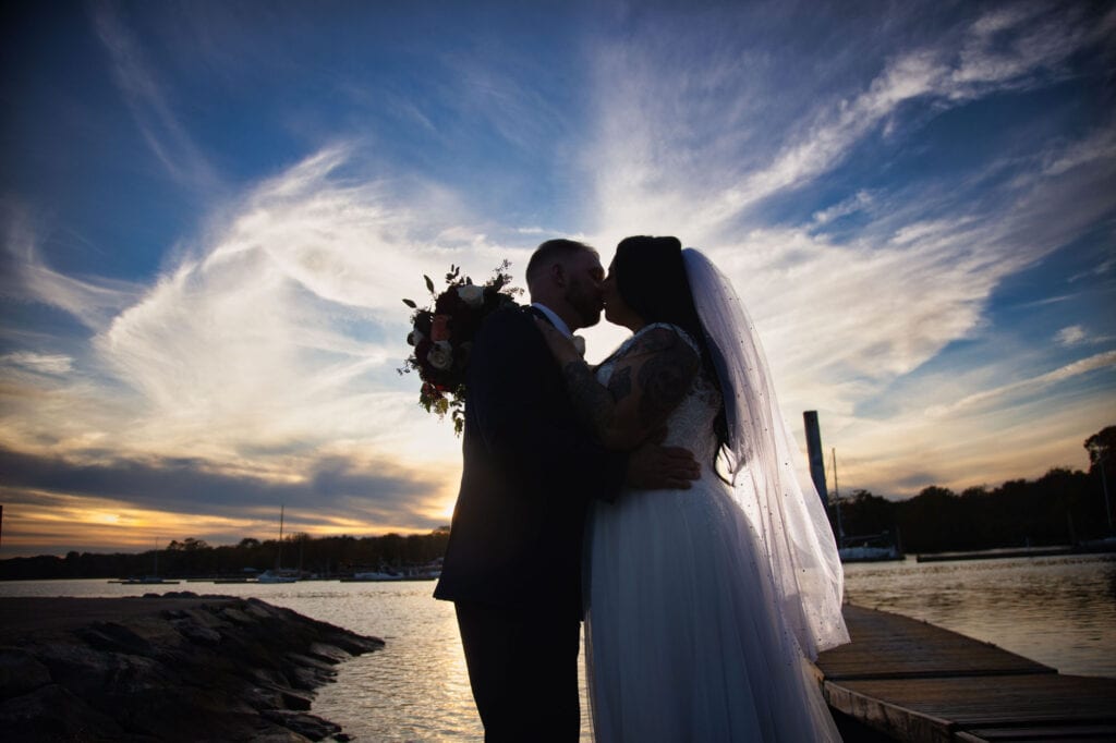 Plus-size-bride-and-groom-in-silhouette-kissing-front-of-epic-sunset
