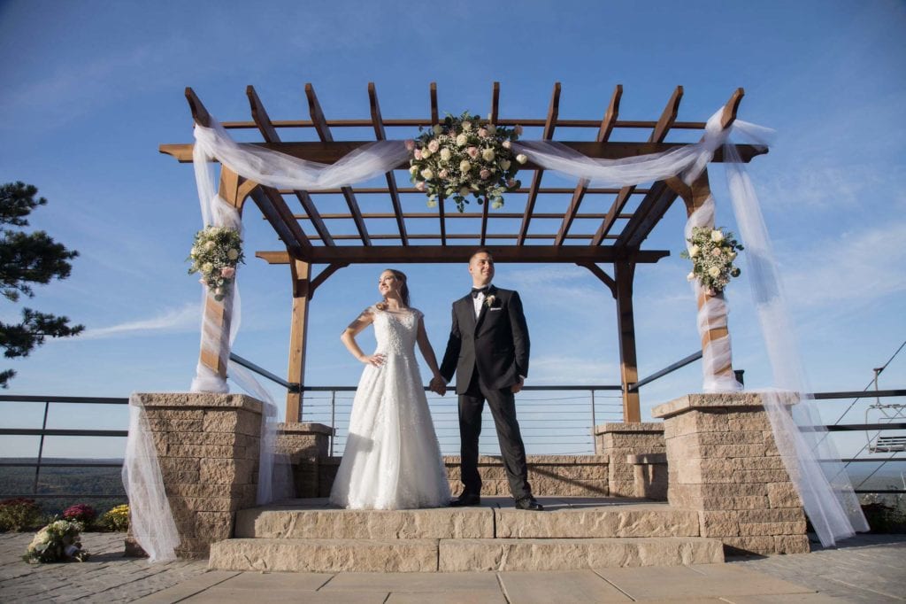 bride and groom under veranda on mountain top with blue sky -wedding venue -Resort style