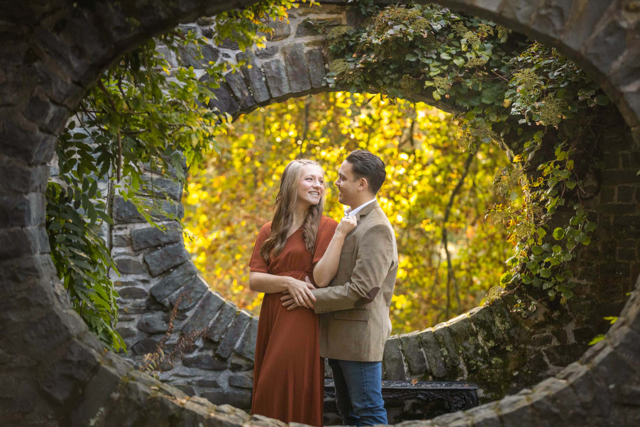 Caucasian engaged couple posing in front of vineyard at Grey Towers in fall foliage