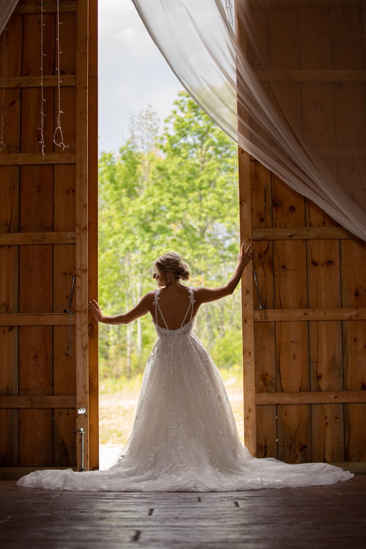 Bride standing in front of open barn door
